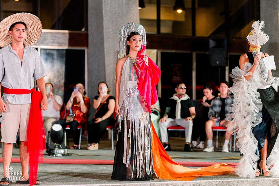 Models wearing avant-garde outfits, including a fringed silver gown and a traditional woven hat, at the Philippine fashion show