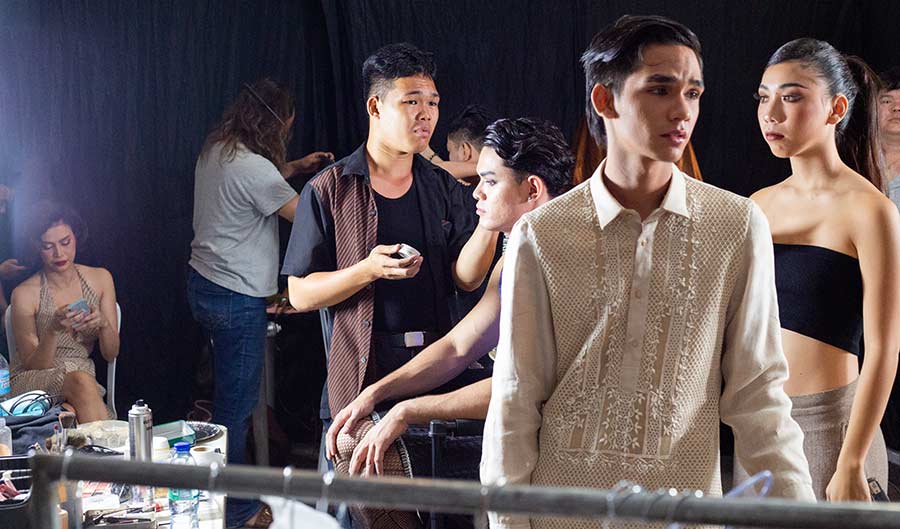 Backstage at a fashion show, makeup artists and models finalizing hair and makeup