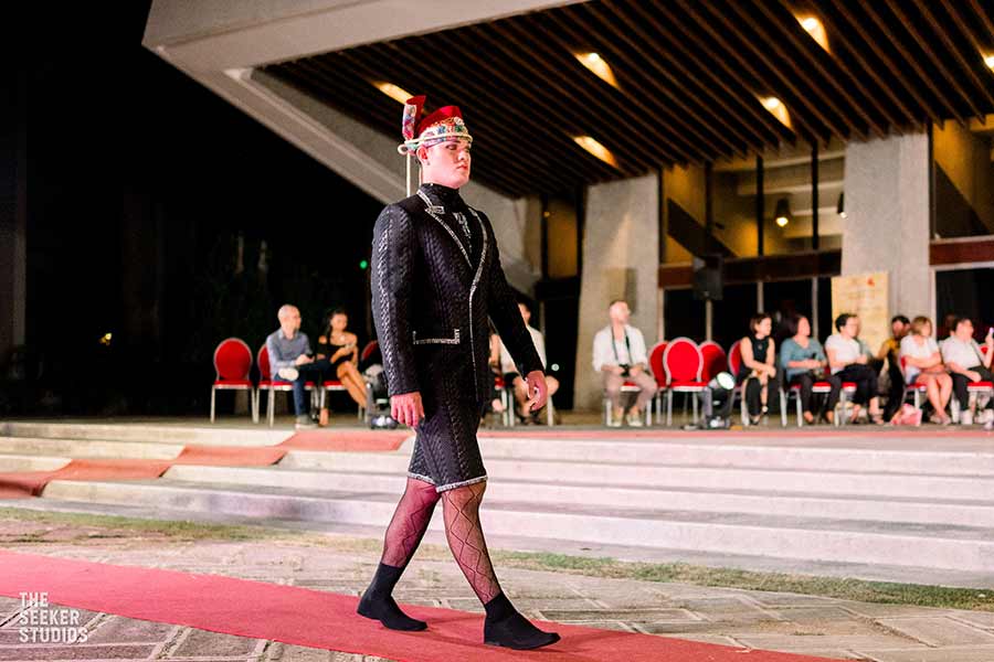 Model in black suit with silver embroidery and red headdress in Dumaguete