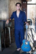 Man in relaxed navy blue linen suit, barefoot, with guitar, featuring a double-breasted jacket and trousers