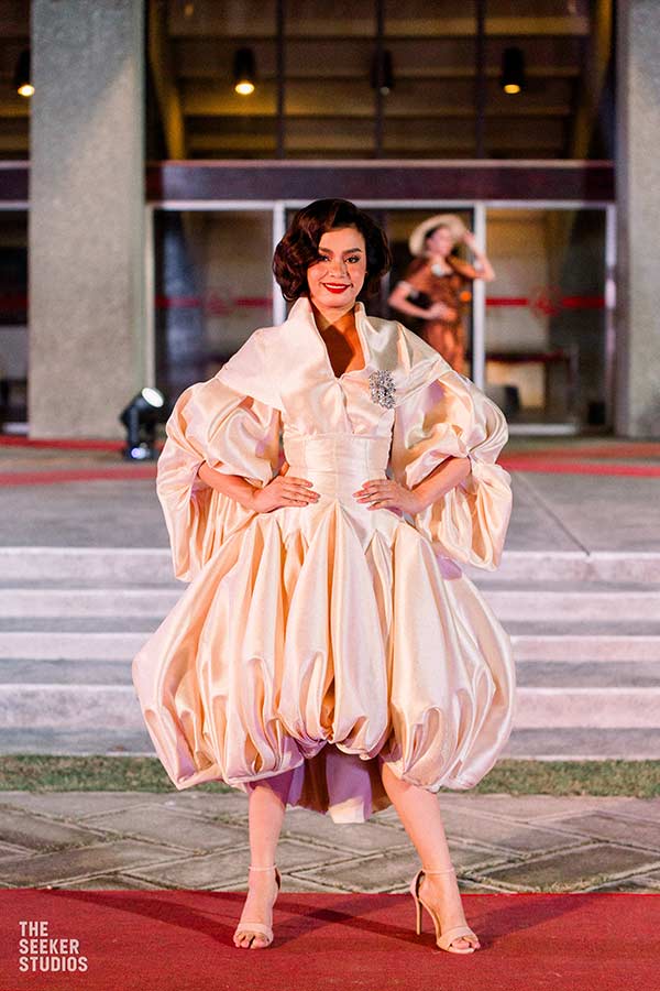 Model in a voluminous cream dress from Josip Tumapa's collection on the runway