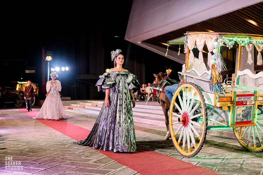 Models in gowns walking beside a traditional carriage at the Philippines Fashion Show