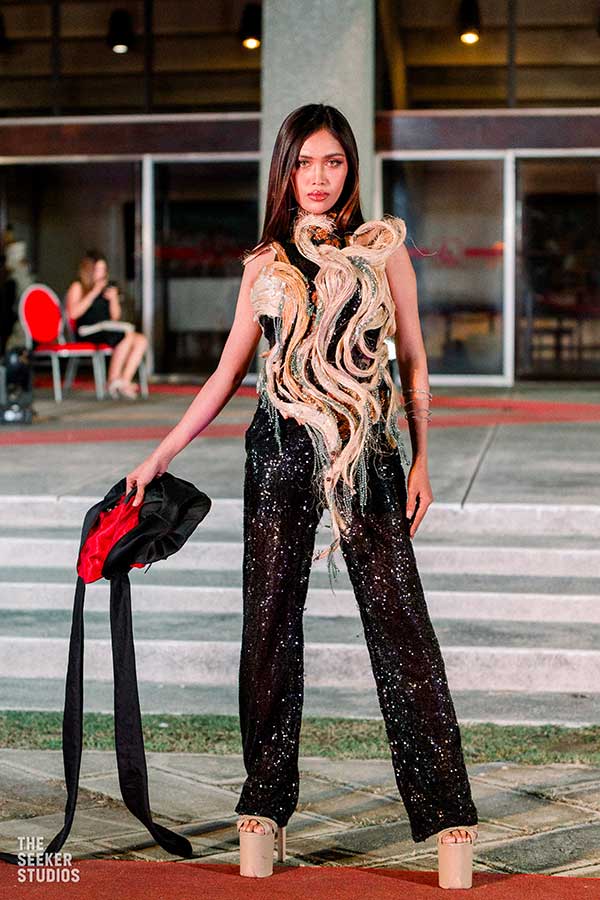 Model in a black sequined jumpsuit with beige details by Tingting Delfin at the show