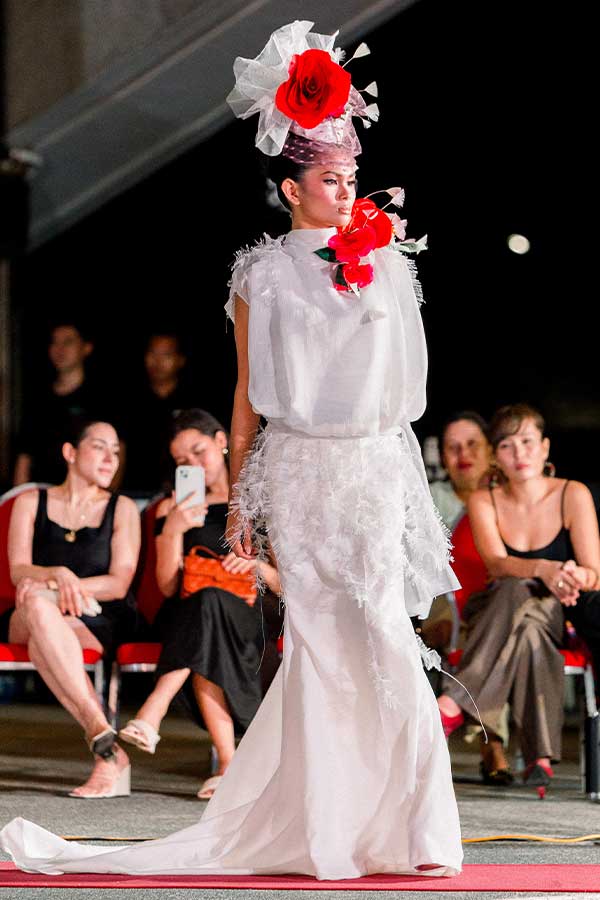 Model wearing a white feathered gown with a bold red floral headpiece at the Philippines