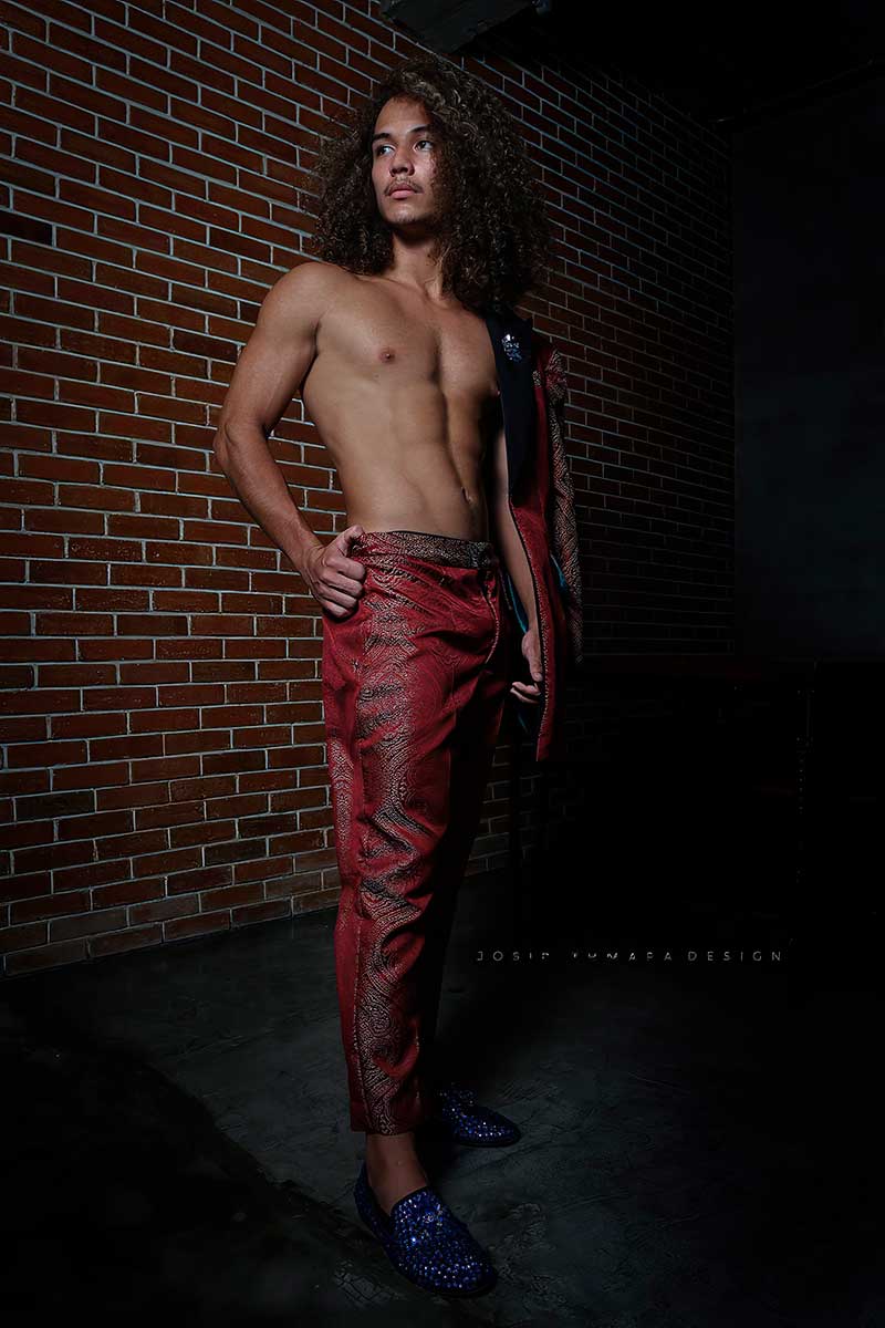 Jacket draped over the shoulder with straight trousers and bare torso, captured in a side-view modern evening menswear pose