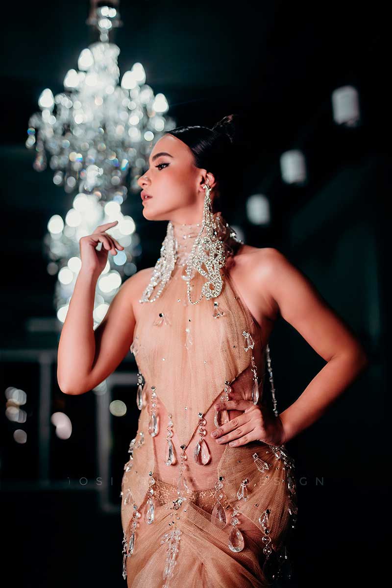 Sheer nude evening dress with crystal drop embellishments arranged across the bodice and skirt, shown in frontal portrait view