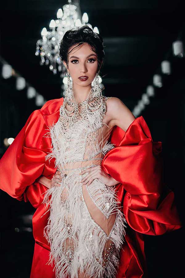 Evening dress featuring feather textures across the bodice and pronounced red sleeves shaping a vertical line