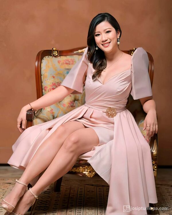 Woman in a light pink dress with traditional Filipina Terno sleeves on a chair