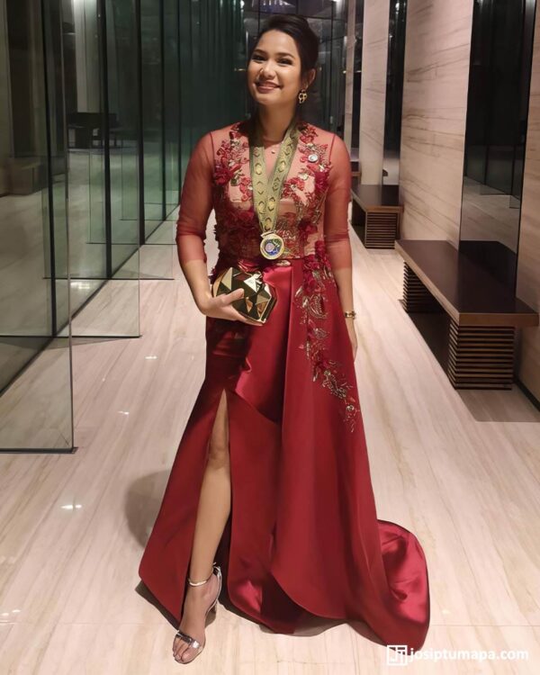 Smiling woman in a custom red evening dress with floral embroidery at a formal event