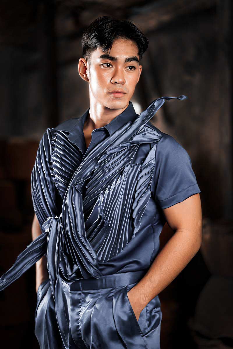 Men’s satin runway look with asymmetric draping, pleated surface accents, and layered construction in rich azure tones