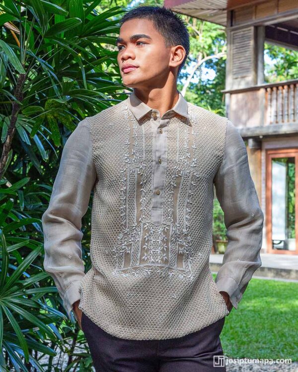 Handwoven piña Barong Tagalog with intricate embroidery, worn by a young man outdoors with tropical greenery and a heritage house