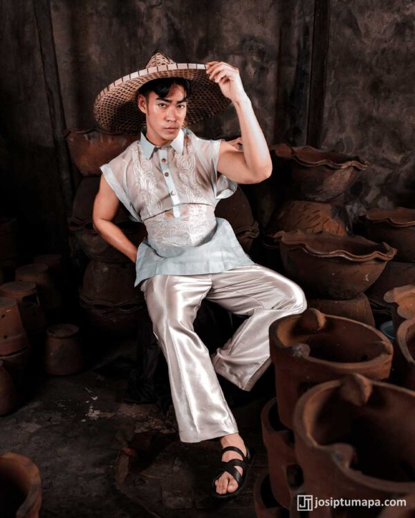 Modern sleeveless Barong Tagalog with embroidery, metallic satin trousers, and woven salakot hat, set in a rustic pottery workshop.