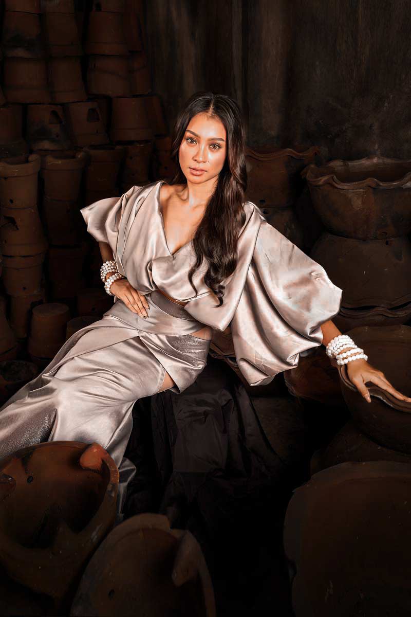 Filipiniana silver dress with draped sleeves, soft waist definition, and fluid skirt in a relaxed seated pose