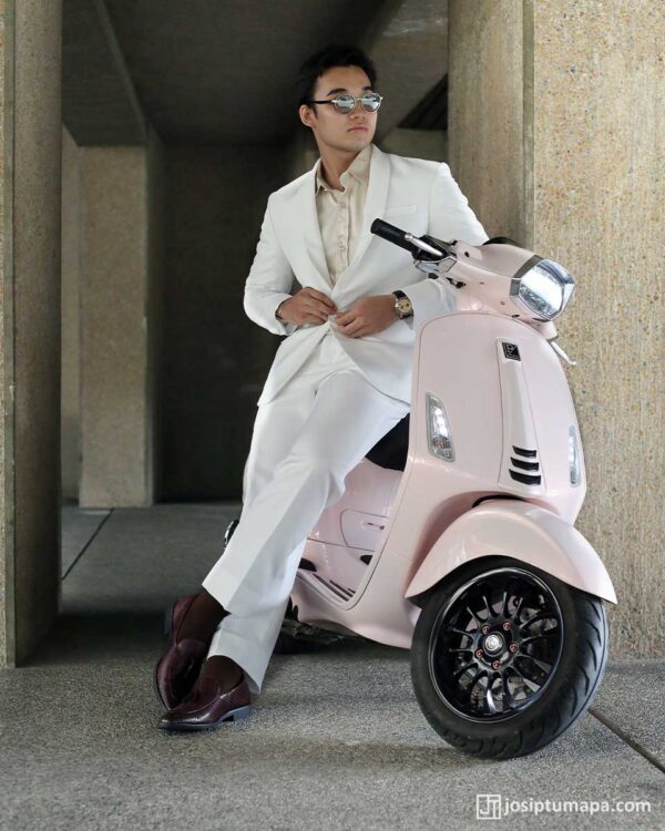 Man in tailored white suit with pink Vespa, modern urban style