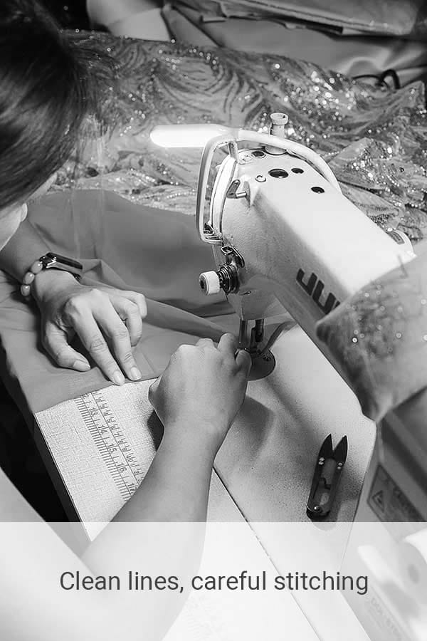 Seamstress stitches fabric using an industrial sewing machine with ruler and guide