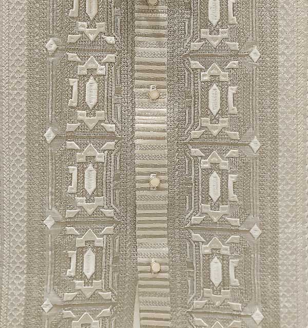 Close-up of machine-made embroidery on piña cocoon barong, showing uniform geometric pattern