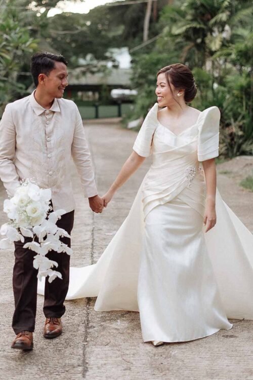 Bride in minimalist Filipiniana Terno wedding gown walking with groom in Barong Tagalog