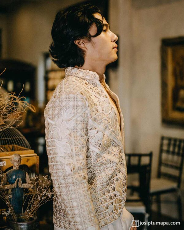 Side profile of a man wearing an avant-garde ivory Barong Tagalog with hand-embroidered lattice and floral detailing