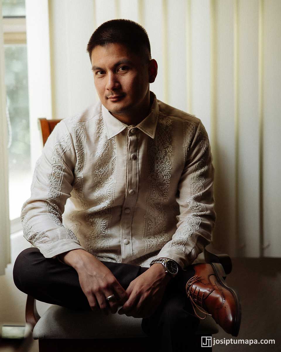 Seated man wearing a formal Barong Tagalog with traditional embroidery in a composed portrait