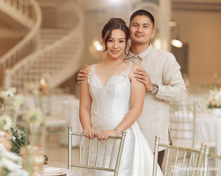 Bride and groom standing together with groom wearing a formal Barong Tagalog and holding the bride by the shoulders