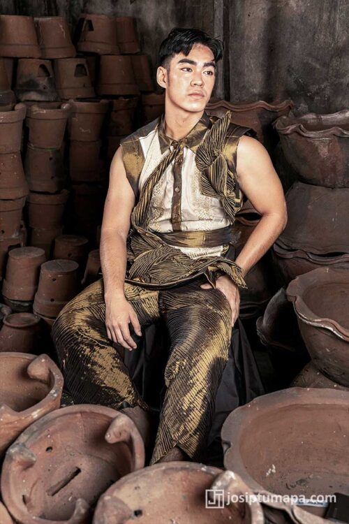 Men’s bronze Filipiniana-inspired ensemble with dense pleating and sleeveless form, seated among clay pottery