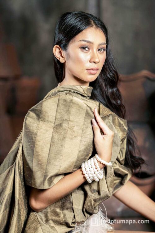 Filipiniana terno in muted gold tone with butterfly sleeves, feather waist detail, and layered pearl bracelets