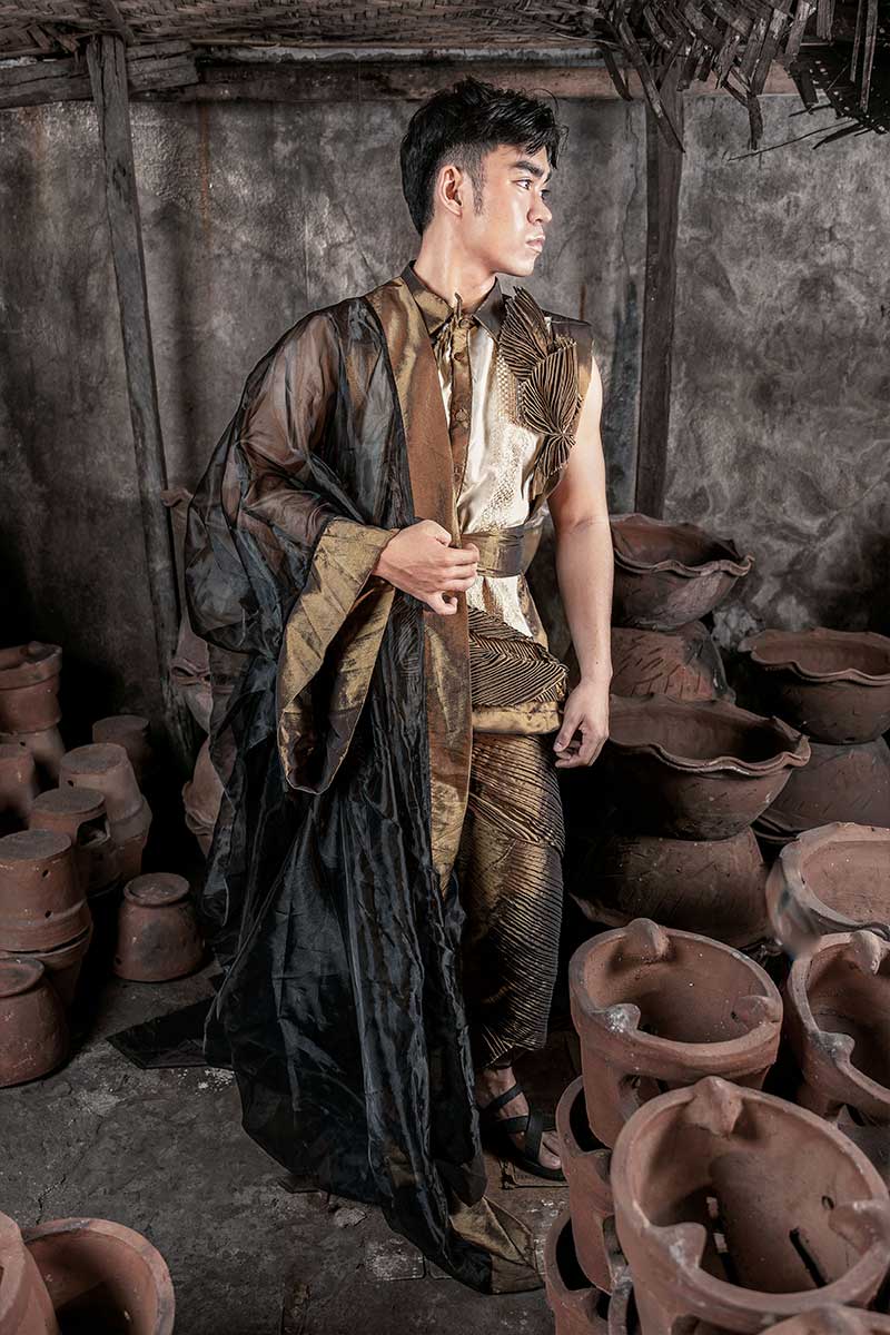 Male Filipiniana-inspired ensemble in bronze-gold tones with pleating and asymmetrical draping, photographed in a pottery workshop