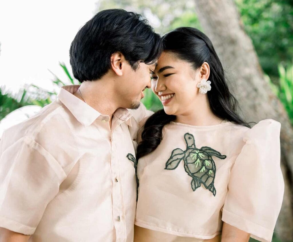 Couple wearing modern Filipiniana and Barong with sea turtle embroidery, soft butterfly sleeves and beige tones outside