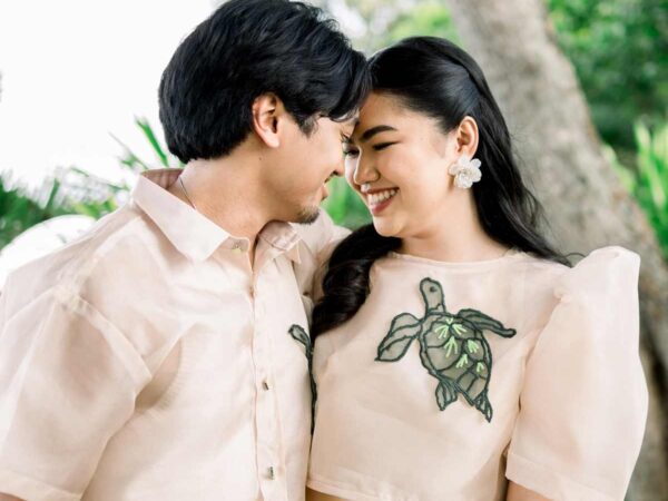 Couple wearing modern Filipiniana and Barong with sea turtle embroidery, soft butterfly sleeves and beige tones outside