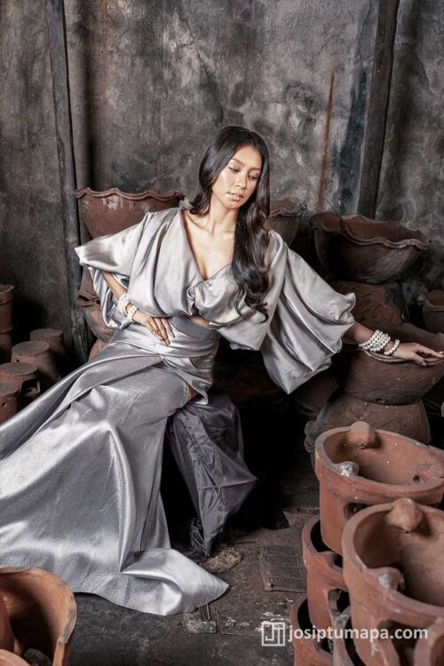 Filipiniana silver dress with draped sleeves, soft waist definition, and fluid skirt in a relaxed seated pose