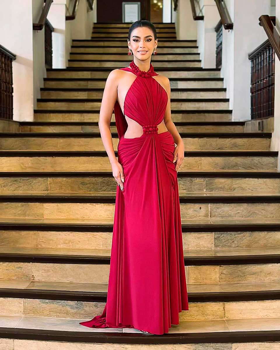 Alt text: Long red evening gown with draped bodice, halter neckline, side cutouts, and floor-length silhouette