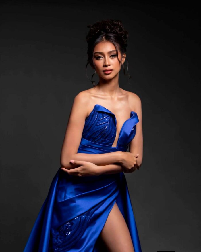 Close portrait of royal blue gown highlighting neckline, drape, and soft light on the upper body
