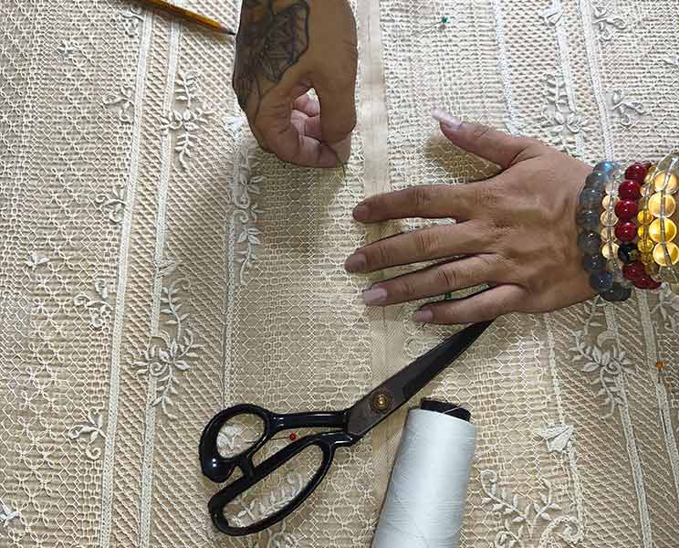 Hands working on embroidered fabric during the making of a custom Barong Tagalog