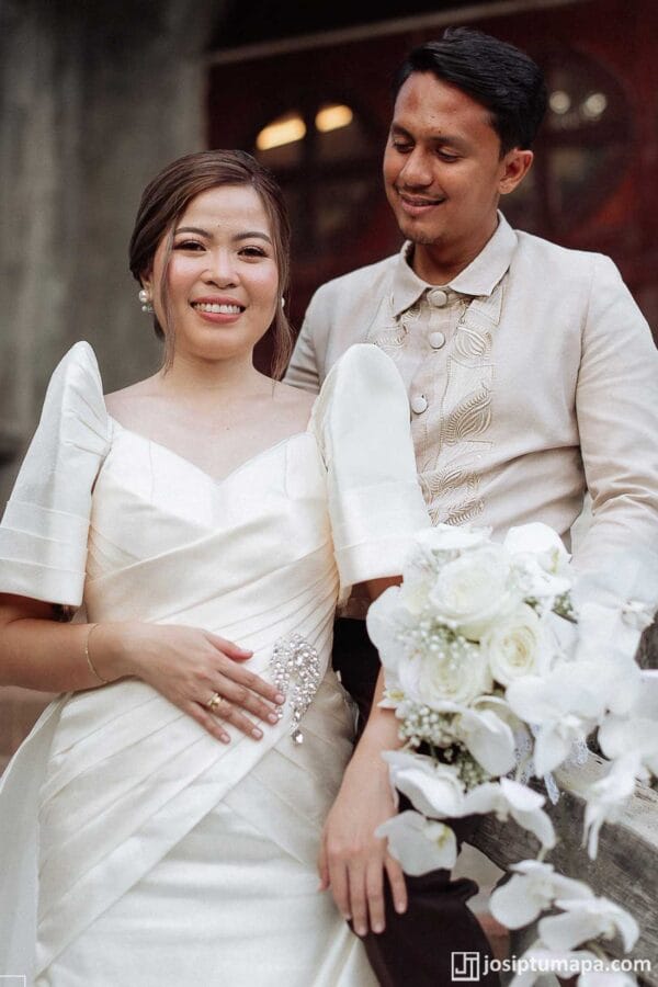 Bride in a minimalist white wedding dress beside a groom wearing a Coat Barong Tagalog with botanical embroidery