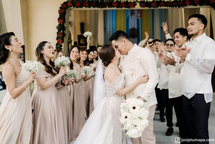 Groom in a piña cocoon silk wedding Barong Tagalog with ethnic-style ornament beside the bride and wedding guests