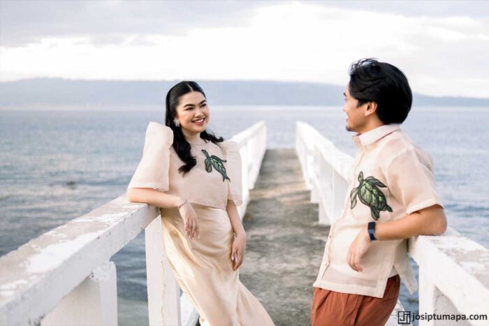 Couple in matching modern Barong-inspired wedding outfits during an outdoor beach ceremony by the sea