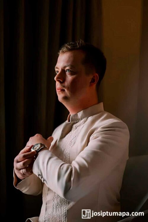 Cream Coat Barong in an Evening Formal Setting Man wearing a cream coat-style Barong Tagalog in a dark interior while adjusting his sleeve
