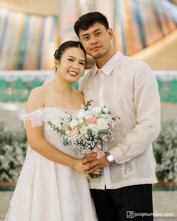 Bride and groom at their wedding, with the groom wearing a floral embroidered Barong Tagalog in piña cocoon silk